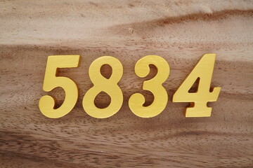 Golden Arabic numerals on a real brown and white wooden floor number 5834