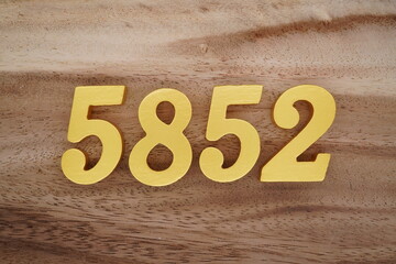 Golden Arabic numerals on a real brown and white wooden floor number 5852