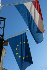 Flags of the Netherlands and the European Union fluttering in the wind attached to flagstaffs