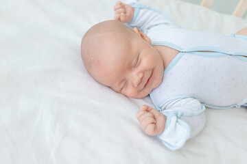 smiling or laughing in a dream, a newborn baby boy sleeps for seven days in a cot at home on a...