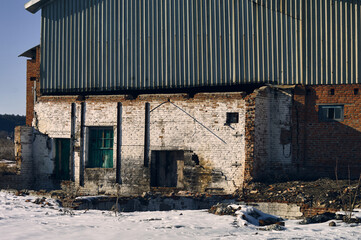 An old abandoned warehouse, brick walls have already begun to collapse, the roof is covered with...