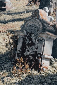 Vertical image of old gravestone at abandoned ancient cemetery. Damaged tombstone at the old churchyard. Forgotten cemetery, unknown grave