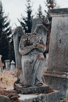Damaged gravestone, beheaded stone angel sculpture at abandoned ancient cemetery. Forgotten cemetery, unknown grave. Selective focus. Vertical image