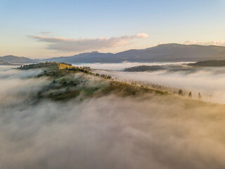 Mountain settlement in the Ukrainian Carpathians in the morning mist. Aerial drone view.