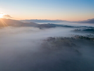 Obraz premium Flight over fog in Ukrainian Carpathians in summer. Mountains on the horizon. Aerial drone view.