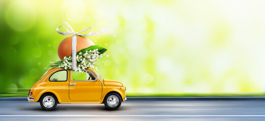 Yellow car carrying an easter egg atop with lilies of the valley bunch. Happy Easter background