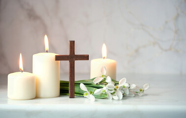 Fototapeta na wymiar Wooden cross, snowdrops flowers and candles on table, blurred abstract background. Religious church holiday. symbol of faith in God, Christianity Feast, Easter, Palm Sunday, Lent