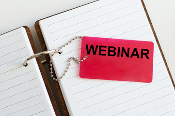 A business card with webinar text on the background of an open notebook on the table, a business concept