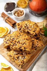Pumpkin blondie bars with chocolate and walnuts top view. Brownie pie slices on a serving wooden board on a light gray culinary background. Baking for Thanksgiving	