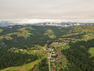 Fototapeta premium Green slopes of Ukrainian Carpathian mountains in summer. Cloudy morning, low clouds. Aerial drone view.