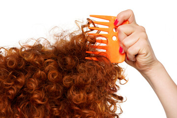 Close up pf red curly hair and hand with comb, isolated on white. 