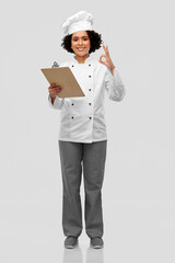 cooking, culinary and people concept - happy smiling female chef in toque and jacket with clipboard showing ok gesture over grey background