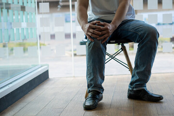The man sat on his chair, clutching his knees in pain. suffering from osteoarthritis medical concept