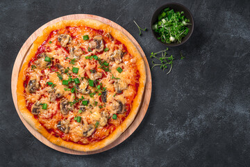 Pizza with cheese, mushrooms and tomatoes on a black background.