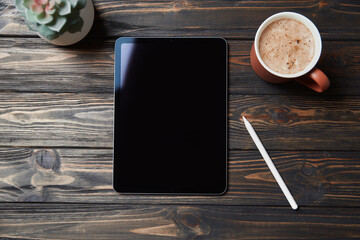 Tablet pc, stylus and cup of coffee on a wooden background.