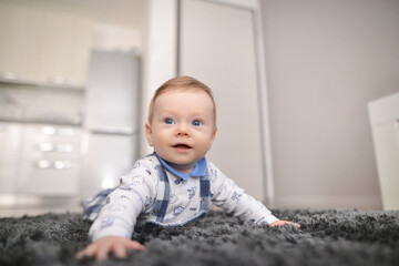 Fototapeta premium Crawling baby on carpet at home. Beautiful baby lies on a fluffy carpet.