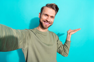 Fototapeta premium Photo of positive nice man shoot selfie palm demonstrate empty space wear pullover isolated blue color background