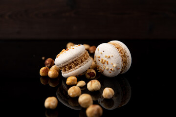 Macarons mit Heselnuss, schwarze Hintergrund, zwei Stück.
