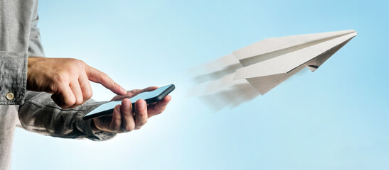 A paper airplane flies away from a smartphone in the hands of a man. The concept of sending messages.
