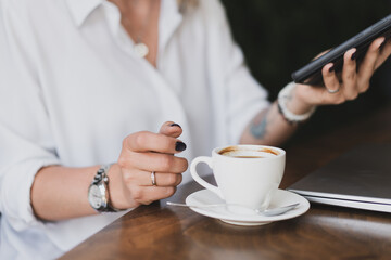 Close-up of women's hands with a phone and a cup of coffee at a table in a cafe