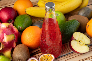 Fruit drink in glass bottle and frsh fruits on wooden background
