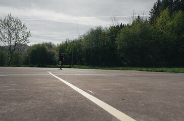 Fototapeta premium BOY IN BLACK TRACKSUIT HITS THE BALL WITH HIS FOOT ON AN OUTDOOR FUTSAL FIELD