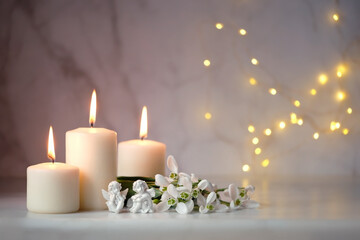 Obraz na płótnie Canvas Cute angels, snowdrops flowers and candles on table, blurred abstract background. Religious church holiday. symbol of faith in God, Christianity Feast. Romantic relaxation composition
