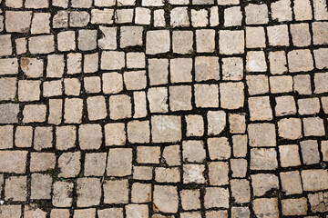 Mosaic of small marble cubes. sidewalks and squares formed by stone carpet with squares. Old cobblestones. High quality photo