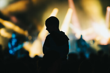 Fototapeta na wymiar Silhouette of a child in a audience crowd on a concert