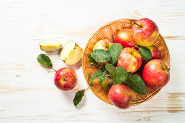 Fresh ripe red apples in the basket at white wooden table. Top view.