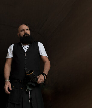 Copy space image of a mature man with nice beard dressed in elegant waistcoat and male skirt who is in a tunnel looking away