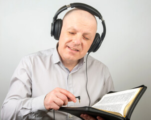 bald man with headphones on his head and an open plug in his hand. Search for a sound source