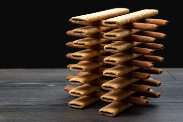 Pyramid of sweet crispy cookie sticks with reflection on dark background. confectionery sweet products. high-calorie food for tea and coffee