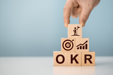 OKR Objectives, Key and Results wooden cube blocks on blue background. Business target and drive...