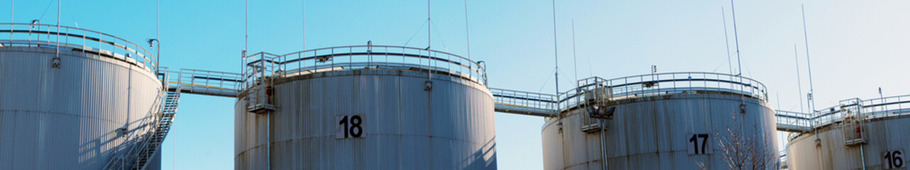 Panoramic view of four industrial oil petroleum storage tanks on sunny day