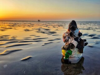 A vandalized idol of Lord Ganesha on a beach denoting disrespect and pollution