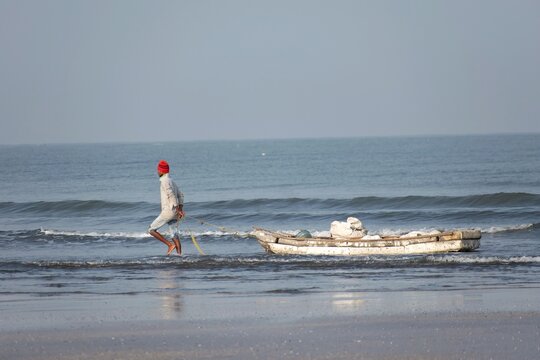 A picture of a fisherman getting ready for fishing with his boat at beach. They do this for their bread and butter. 