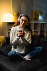 Obraz premium woman is listening to a music and drinking coffee or tea at home
