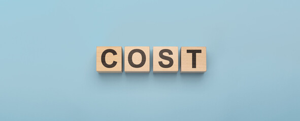 cost word concept from wooden blocks on blue. Cost, expense or company profit and loss concept, cube wooden blocks with alphabet combine word cost on wooden desk, analyze spending or payment