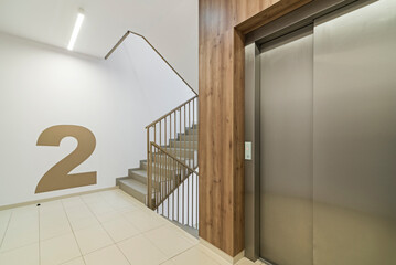 Nowoczesny korytarz z klatką schodową i windą w bloku mieszkalnym w jasnych kolorach. - obrazy, fototapety, plakaty
