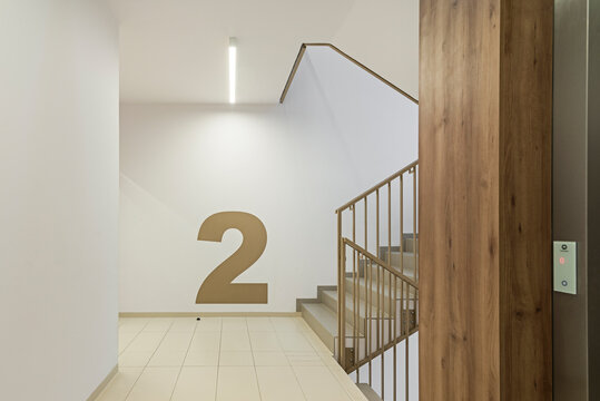 Nowoczesny korytarz z klatką schodową i windą w bloku mieszkalnym w jasnych kolorach.
