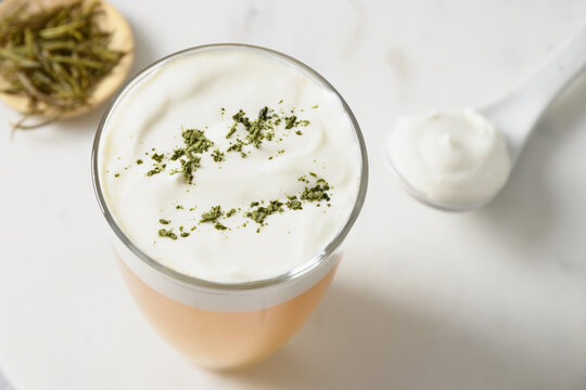Traditional Chinese Tea with layer of creamy foam topped matcha powder on white background. Asian trendy beverage. Thai milk tea. Close up.