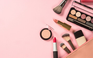 Make up products at pink background with cosmetic bag. Eye shadow, lipstick, powder, brushes and...