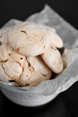 Chocolate meringue lies on a black table. Meringue in a bowl. Glossy black table.