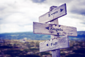 even angels fall text quote written in wooden signpost outdoors in nature. Moody theme feeling.