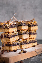 Shortbread cookies with jam are neatly folded and tied with a thread. Vertical photo of cookies on a gray background with coffee beans.