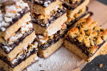 square shortbread cookies with jam close-up. Coffee beans sprinkled with powdered sugar are scattered on the table. On a gray background.