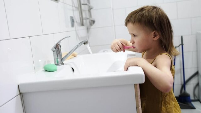 Cute baby toddler brushing his teeth in the bathroom at the sink. Child brushing his teeth U-Shaped Toothbrush