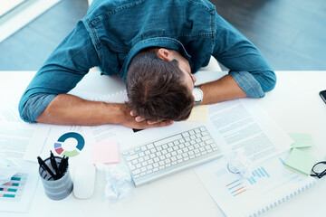 Even he needs to refresh every now and then. High angle shot of an exhausted young businessman taking a nap on his desk in his office.