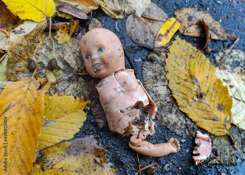 Wall mural Little broken doll forgotten on the street. Symbol of a broken childhood